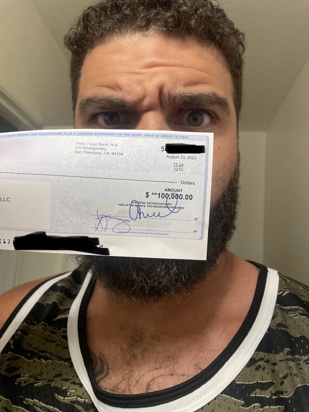 Coach Crim peeking over a $100,000 assignment check